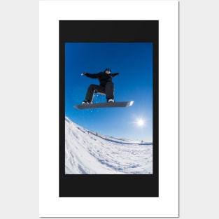 Snowboarder jumping against blue sky Posters and Art
